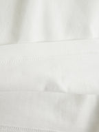 6.2オンスのタフな生地を使用したロングスリーブTシャツの袖リブと、左裾の青い戦績タグの接写。