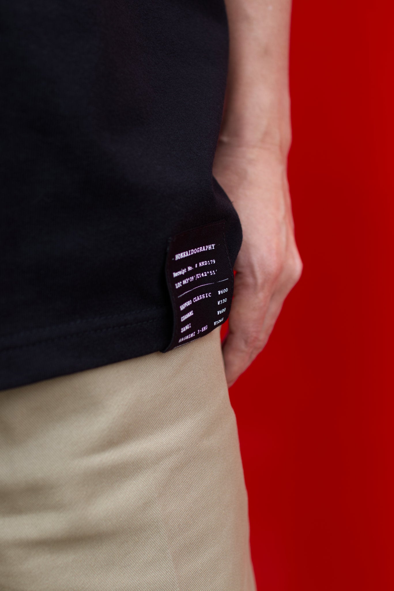 HKD Receipt Tシャツ ブラック レシートタグ ディテール クローズアップ 男性モデル着用」