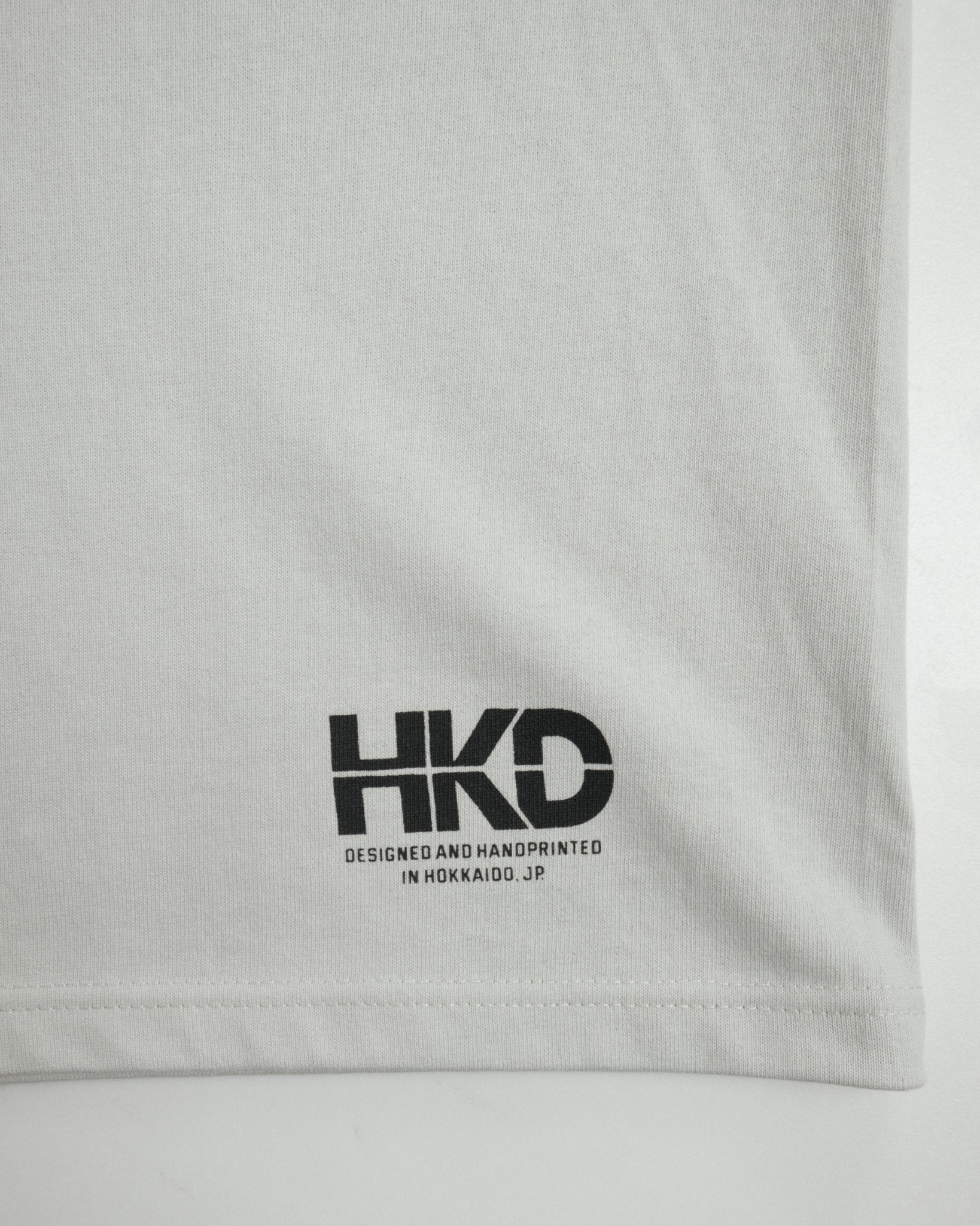 MONO TREE Tシャツ フロストグレー 左裾 HKDロゴ クローズアップ