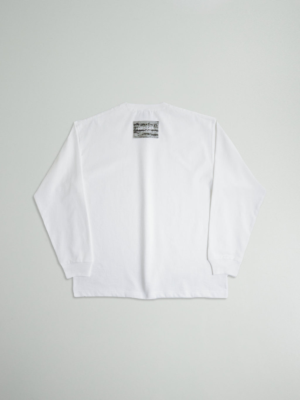 ホワイトのLONG SLEEVE TEE背面全体。バックネックに配置された白樺模様のブランドタグ。